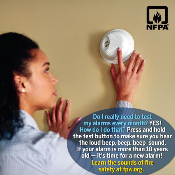 Woman checking smoke alarm with tip on how to test the alarm